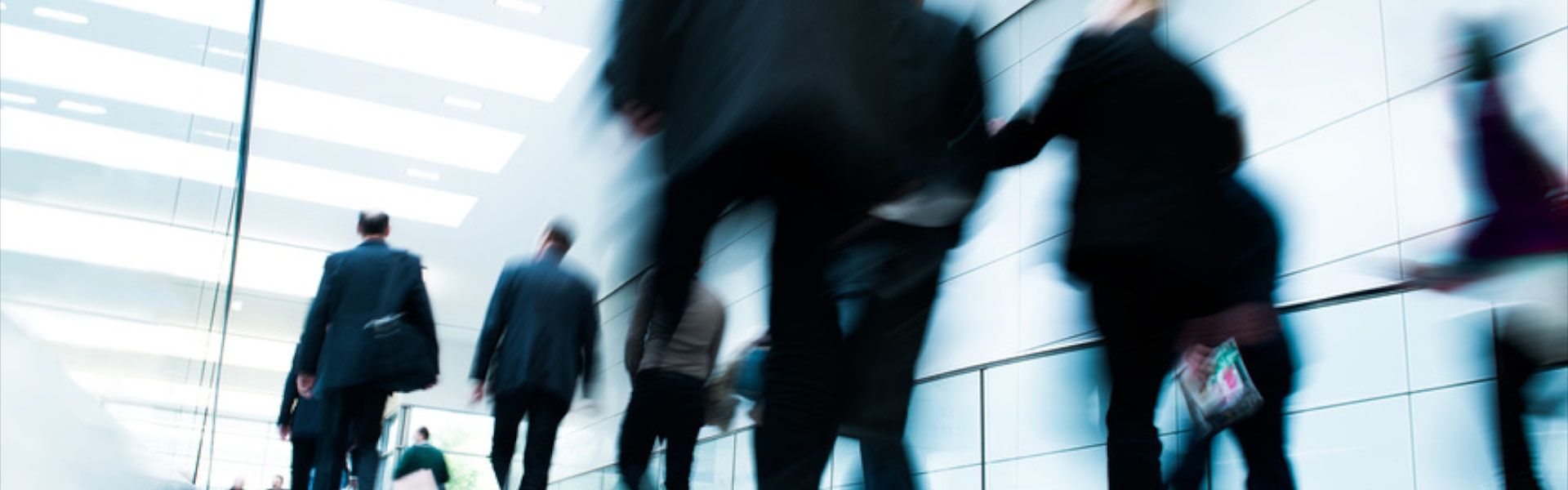 Image of business workers in suits walking down a busy hallway. 